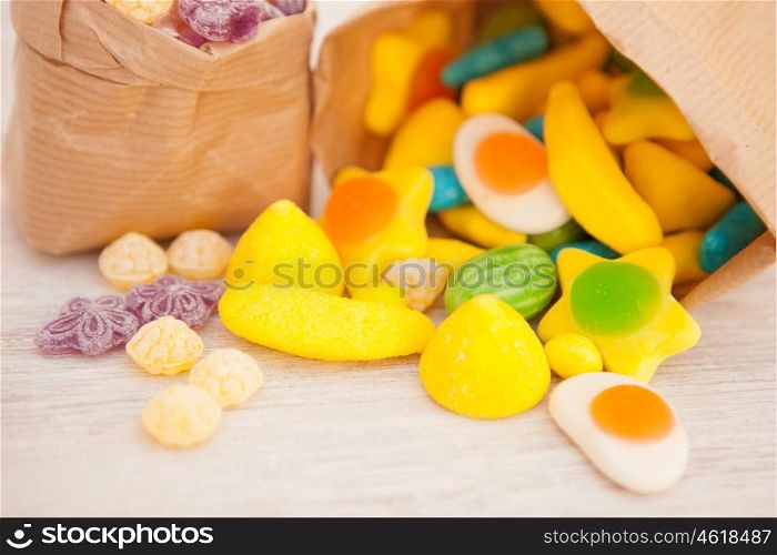 Paper bags stuffed with candy on a gray wooden background