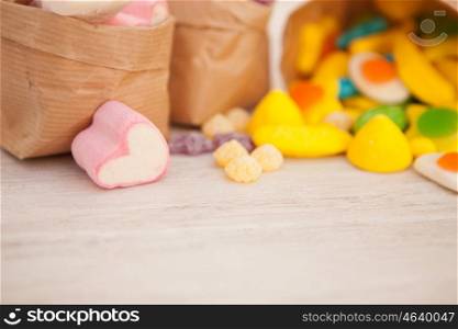 Paper bags stuffed with candy on a gray wooden background. Soft focus