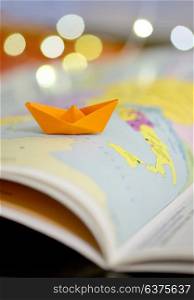 Paper boat on a atlas book map of the world