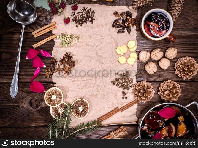 paper bundle of brown paper and ingredients for making mulled wine on a brown wooden background, empty space in the middle