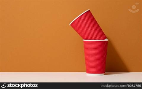paper cardboard red cups for coffee, orange background. Eco-friendly tableware, zero waste