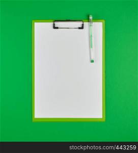 paper clipboard and pen on a green background, top view