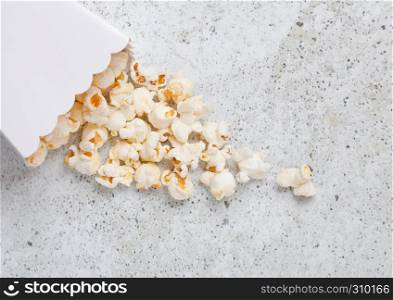 Paper container with fresh salted popcorn on stone background