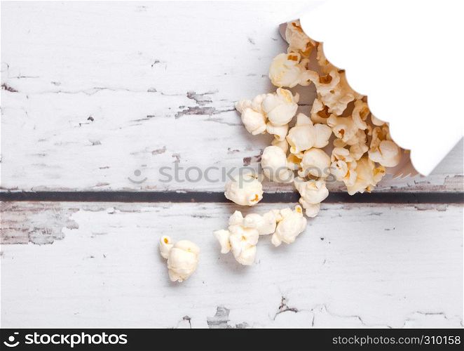 Paper container with fresh salted popcorn on wooden background