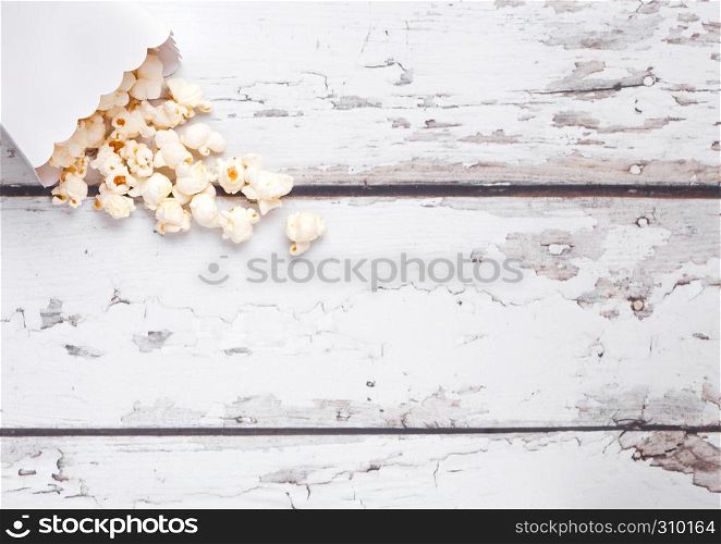 Paper container with fresh salted popcorn on wooden background