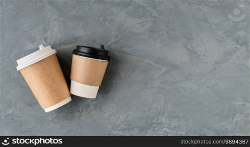 Paper cups for coffee or tea on a gray background from a top view with copy space. Flat lay takeaway coffee or hot drinks. Layout with a minimum of detail