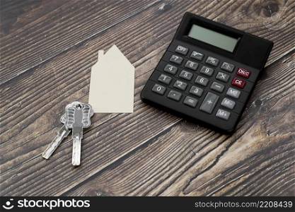 paper cut out house with keys calculator wooden textured surface