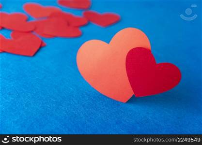 Paper cut red hearts shape on blue textured background with copy space. Concept image. Valentine&rsquo;s day, mother&rsquo;s day, birthday greeting cards, invitation, celebration