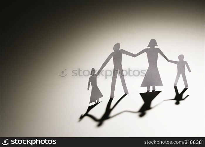 Paper cutout family of four standing holding hands.
