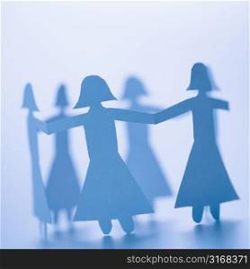 Paper cutout girls holding hands standing in circle.