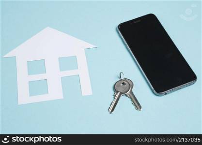 paper cutout house keys with cellphone blue background