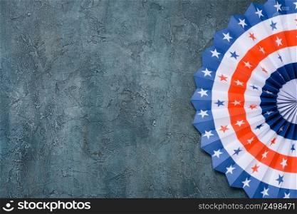 Paper fan US flag color style on grunge rustic background flat lay.