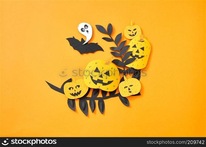 Paper handcraft composition flying bat, leaves,ghost and scary pumpkins on an orange background with copy space. Halloween. Flat lay. Leaves, flying bat, ghost and pumpkin with a scary face on an orange background with space for text. Hand craft paper composition to Halloween. Flat lay