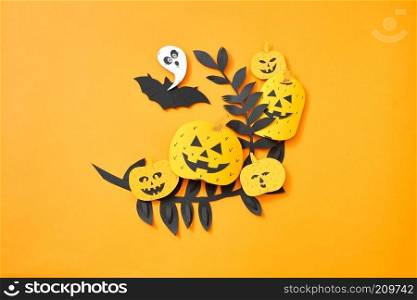 Paper handcraft composition flying bat, leaves,ghost and scary pumpkins on an orange background with copy space. Halloween. Flat lay. Leaves, flying bat, ghost and pumpkin with a scary face on an orange background with space for text. Hand craft paper composition to Halloween. Flat lay