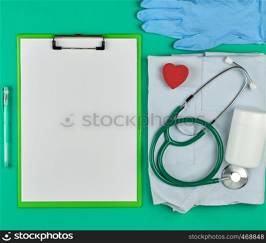 paper holder with empty white sheets, medical stethoscope, pills on a green background, top view, space for writing a prescription