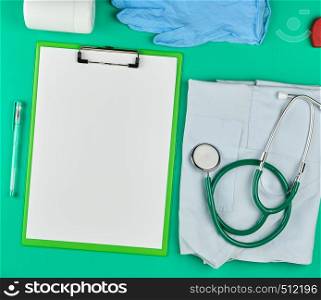 paper holder with empty white sheets, medical stethoscope, pills on a green background, top view, space for writing a prescription