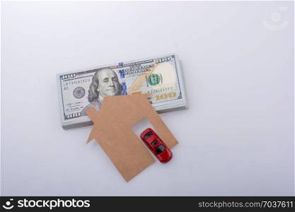 Paper house and a car beside US dollar banknotes