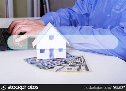 Paper house, money, and man. Mortgage, savings and purchase of an apartment. Money and a small building on the table. The realtor or real estate agent writing the offer.. Paper house, money, and man. Mortgage, savings and purchase of an apartment. Money and a small building on the table.