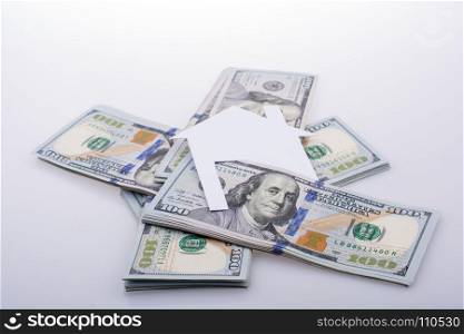 Paper house placed beside a bundle of US dollar banknote