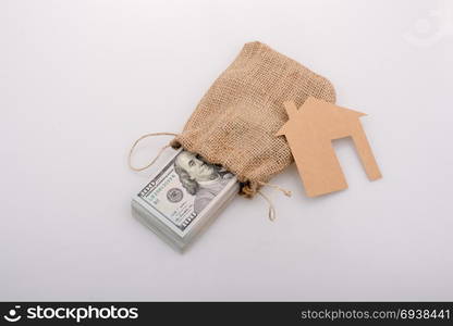 Paper house placed beside a bundle of US dollar banknote