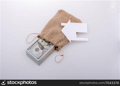 Paper house placed beside a bundle of US dollar banknote