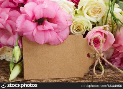 paper note and pile of fresh pink  and white roses on wooden table . pink and white  roses 