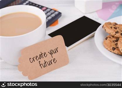 "Paper note with text "create your future" and cup of coffee, cookies and calculator on white wooden background. Paper note with text "create your future""