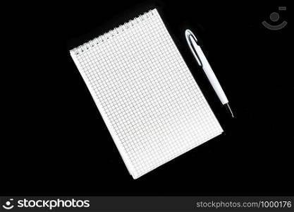 paper notebook with ballpoint pen on black isolated background