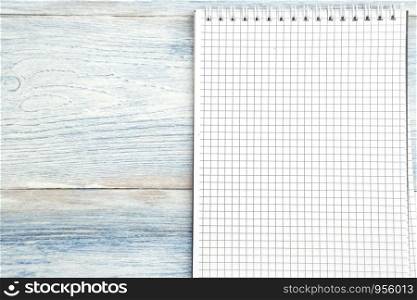 paper notebook with space for text on a light blue old wooden background. top view. flat lay