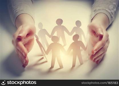 Paper people surrounded by hands in gesture of protection. Concept of insurance, social protection and support. . Paper people surrounded by hands in gesture of protection. Concept of insurance