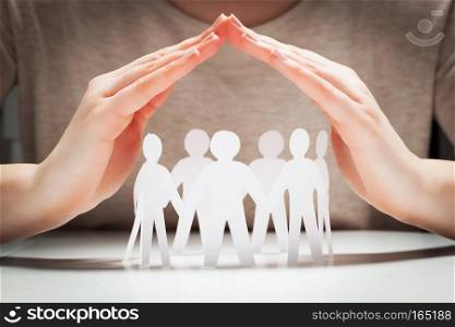 Paper people under hands in gesture of protection. Concept of insurance, social protection and support. . Paper people under hands in gesture of protection.. Concept of insurance