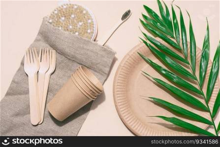 Paper plates, wooden forks and a toothbrush on a beige background, top view. Concept of recyclable garbage, zero waste