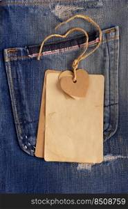 Paper price tag label at jeans background texture. Blue jeans denim fabric