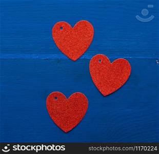 paper red shiny decorative hearts on dark blue wooden background, abstract festive backdrop for valentines day february 14