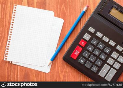 Paper sheets and calculator on wooden background