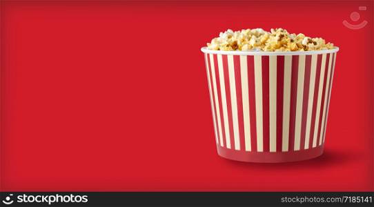 Paper striped bucket with popcorn isolated on red background with clipping path. Concept of cinema or watching TV.