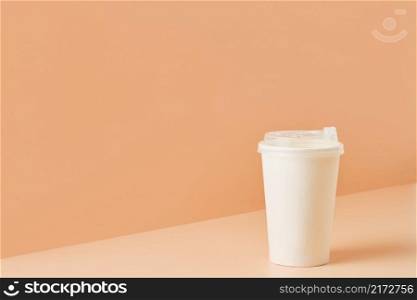 Paper unbranded white glass for drinks on a colored background, close-up with copy space for text.Cardboard eco-friendly cup