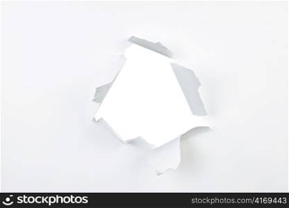 Paper with ripped hole and torn edges over white