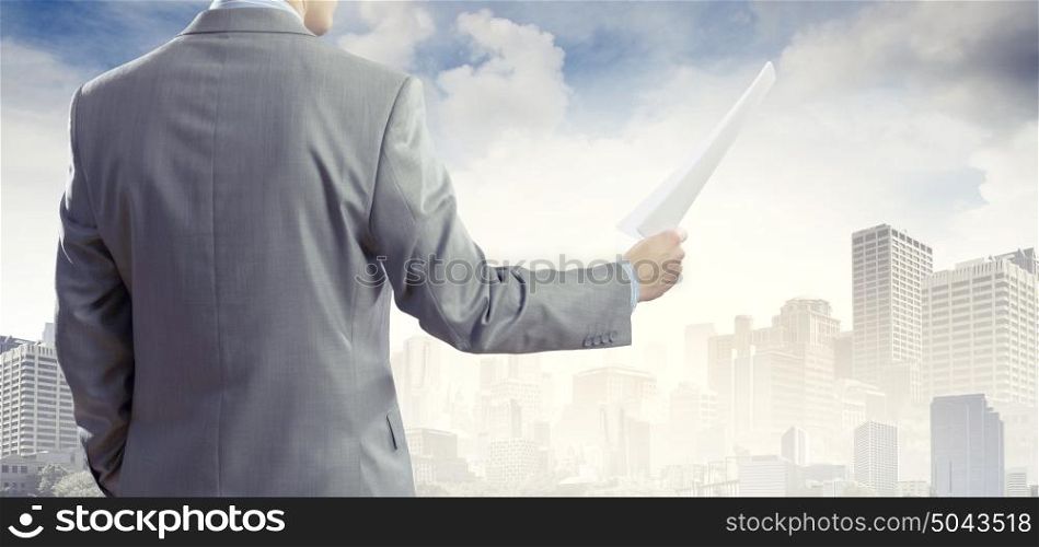 Paperwork. Back view of businessman reading documents in hand