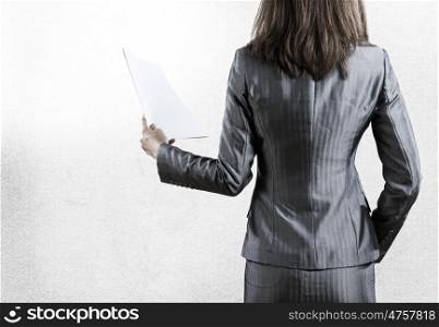 Paperwork concept. Rear view of businesswoman with papers in hand