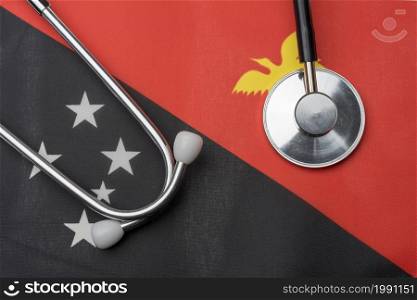 Papua new Guinea flag and stethoscope. The concept of medicine. Stethoscope on the flag in the background.. Papua new Guinea flag and stethoscope. The concept of medicine.