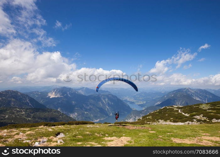 Parachute jumping extreme sport. Paraglider flying over mountains in summer day