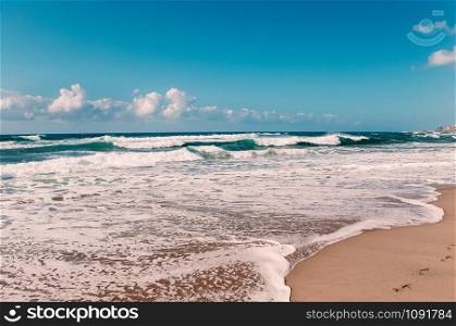Paradise ocean beach, blue sky, white clouds, yellow sand, turquoise waves, panorama view, with footprints in wet sand