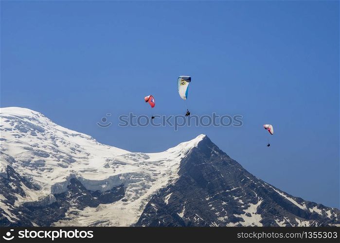 Paragliders looking for thermals amongst the snow caps of the Monte Blanc Massif, Chamonix, France