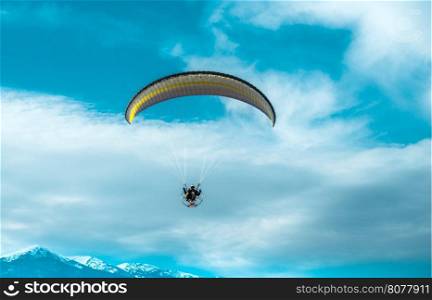 Paragliding fly on blue cloudy sky