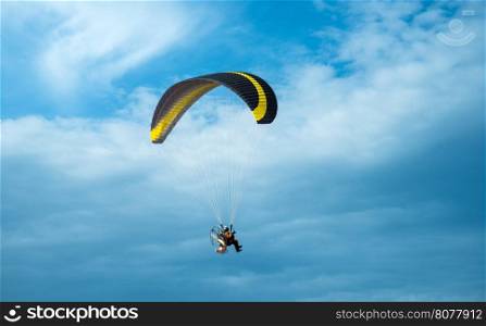 Paragliding fly on blue cloudy sky