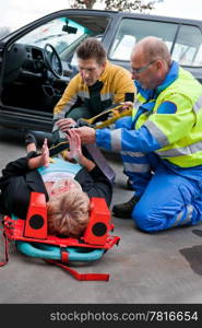 Paramedic and firefighting providing first aid to an injured woman on a stretcher