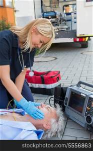 Paramedic helping injured senior patient lying on street