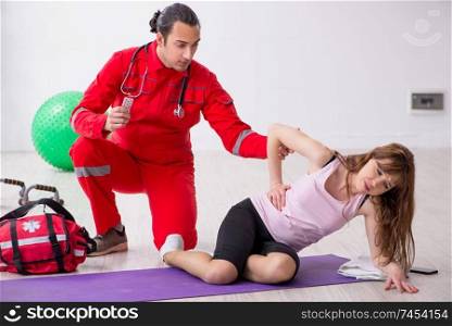 Paramedic in red visiting young woman in gym 