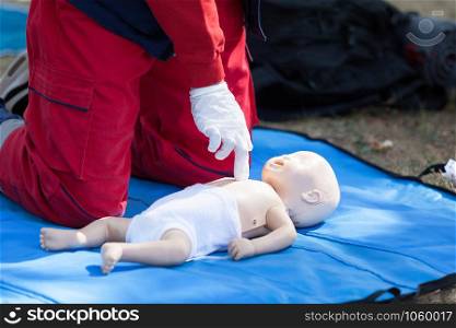 Paramedic performing CPR on baby dummy with two-finger chest compression